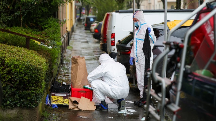 Beamte der Spurensicherung sichern nach einem Messerangriff Beweismittel auf einem Gehweg.