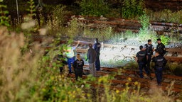 Polizeibeamte untersuchen das Gleisbett nach einem Brand auf der Bahnstrecke in Wuppertal