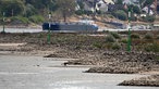 Ein Frachtschiff fährt bei niedrigem Wasserstand auf dem Rhein.