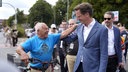 Hendrik Wüst hat seine hand auf die Schulter eines Mannes gelegt, der ein Fahrrad schiebt