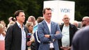 Hendrik Wüst steht in einer Menschenmenge und neben ihm ein Moderator