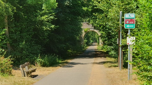 Über den Radweg RAVel bei Clermont-sur-Berwinne führt eine Steinbrücke. Ein Wegweiser  zeigt, dass man hier zu Fuß ins Dorf kommt.