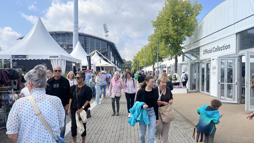 In dem Reitsportstadion sind verschieden Stände aufgebaut und viele Gäste schlendern umher. 
