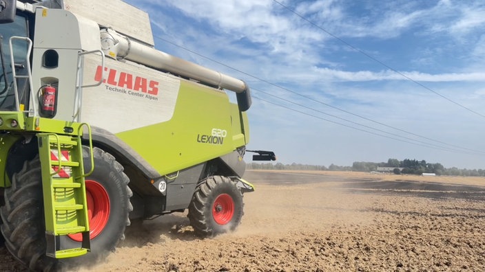 Eine Landmaschine fährt über ein staubiges Feld