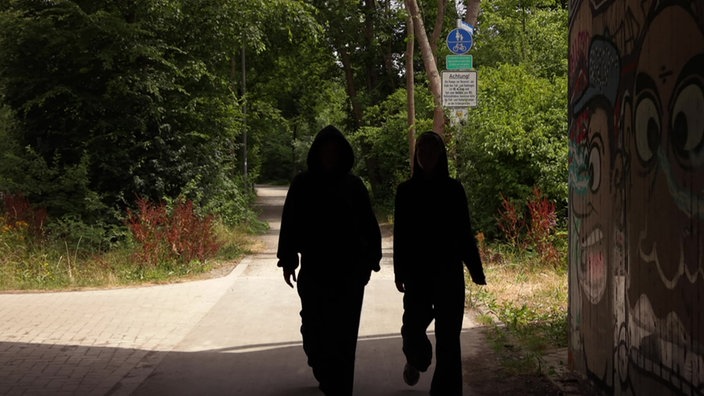 Zwei junge Frauen in schwarzen Houdies von hinten