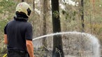Eine Person mit Helm bei den Löscharbeiten im Wald