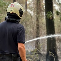 Eine Person mit Helm bei den Löscharbeiten im Wald