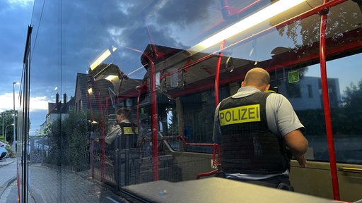 Zwei Polizisten kontollieren Passagiere in einem Linienbus