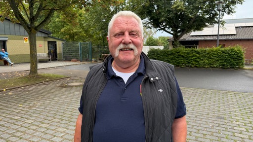 Ein älterer Mann mit Schnurrbart.