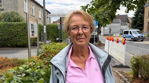 Eine ältere Frau mit Brille schaut in die Kamera.