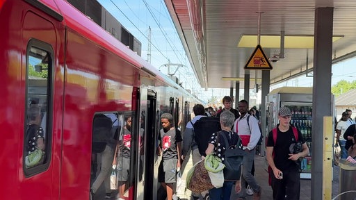 Menschen steigen in einen Zug am Bahnhof Düren ein