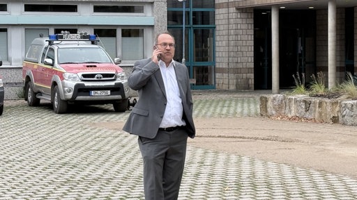 Dürener Landrat Ralf Nolten telefoniert vor einer Feuerwache.