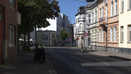 Es ist der Bonner Platz in Düren zu sehen. Die Häuser sind Altbauten und am Straßenrand ist ein Motorrad geparkt.