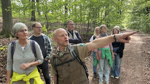 Sascha Wilden zeigt den Teilnehmenden der Wandertruppe etwas in der Ferne.