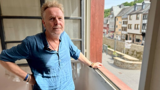 Buchhändler steht am geöffneten Fenster zur Innenstadt.