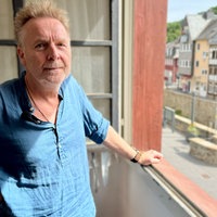 Buchhändler steht am geöffneten Fenster zur Innenstadt.
