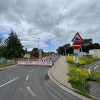 EIne abgesperrte Straße mit einem DUrchfahrt-Verboten-Schild. Im Hintergrund steht ein Bahnübergang. 