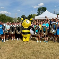 Ganz viele Menschen in Sportkleidung jubeln und halten silberne Luftballons in Form einer 100.000 hoch