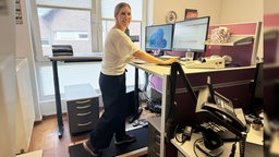 Eine Frau steht an ihrem hohen Schreibtisch, unter ihr ist ein Laufband