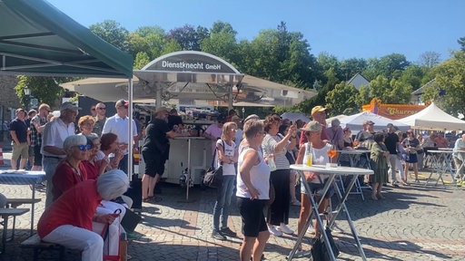 Menschen stehen an einer Theke und Stehtischen auf dem Dankesfest in Bad Münstereifel 