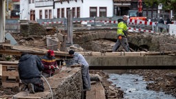 Männer arbeiten an einer Brücke und am Ufer