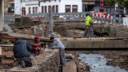 Männer arbeiten an einer Brücke und am Ufer
