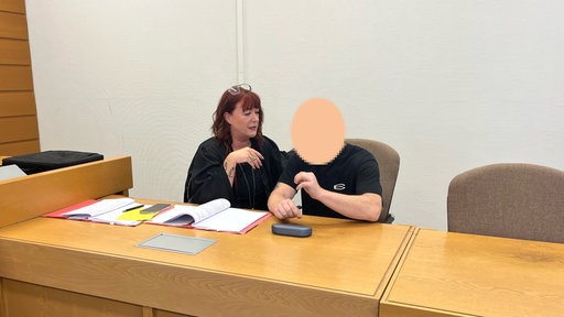 Der Angeklagte im Prozess wegen möglicher Korruption in der JVA Euskirchen sitzt neben seiner Anwältin im Gerichtssaal am Amtsgericht Köln
