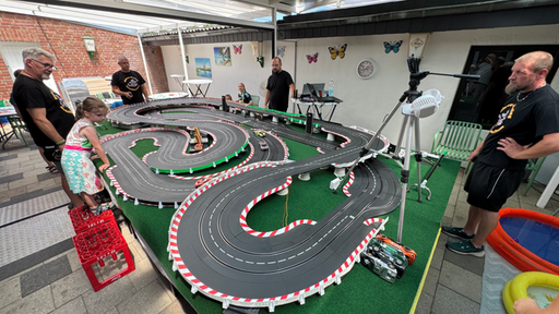 Mehrere Personen spielen an einer Modellautobahn-Rennstrecke