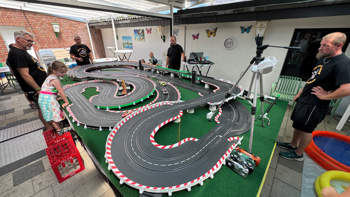 Mehrere Personen spielen an einer Modellautobahn-Rennstrecke