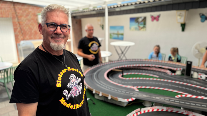 Ein Mann steht an einer großen Modellbahn-Rennstrecke