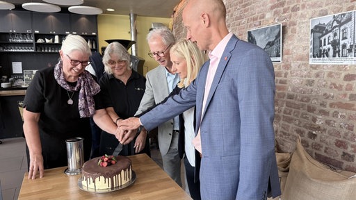 William Verpoorten, Viktoria Verpoorten und weitere Gäste schneiden auf der Jubiläumsfeier von Verpoorten eine Torte an.