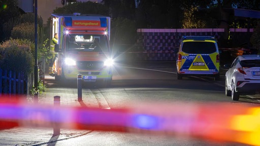 Ein Rettungswagen und ein Polizeifahrzeug stehen in der Nähe eines abgesperrten Tatorts in Wassenberg