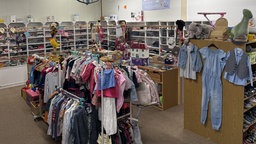 Ein Raum ist mit vollen Regalen und Kleiderständern voller Kinderkleidung ausgestattet