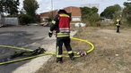 Ein Feuerwehrmann steht vor einem Wasserschlauch