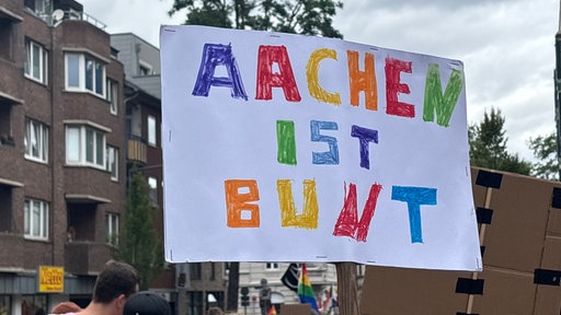 Ein Schild, auf dem "Aachen ist bunt" in verschiedenen Farben geschrieben steht