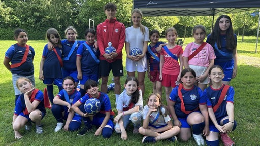 Ein Mädchen und ein Junge stehen mitten in der Mädchenfußballmannschaft