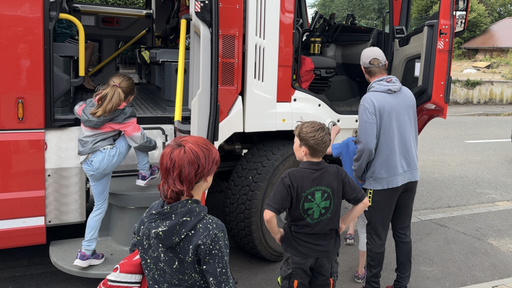 Kinder schauen sich einen Feuerwehrwagen genauer an