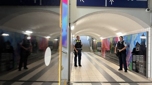 Zwei Polizeibeamte, die in einer Unterführung am Bahnhof stehen.