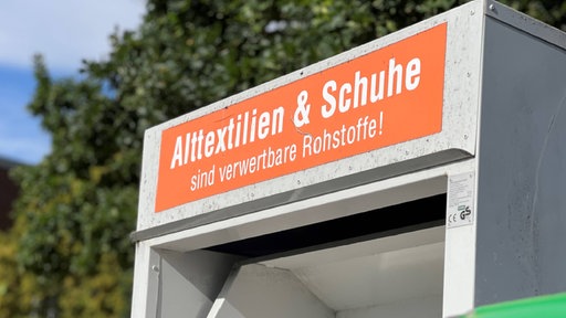 Ein altkleider Container in der Stadt Düren mit einer Klappe zum einwerfen von Kleidern und dem Hinweis Alttextilien und Schuhe