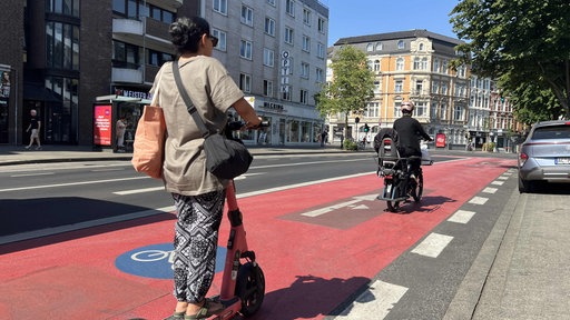 Auf einem Radweg in Aachen fährt ein E-Scooter hinter einem Fahrrad.