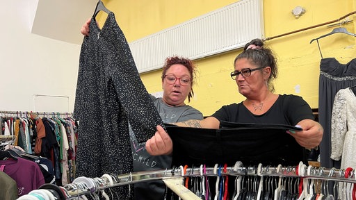 Zwei Frauen diskutieren über Kleidung an einem Kleidungsständer