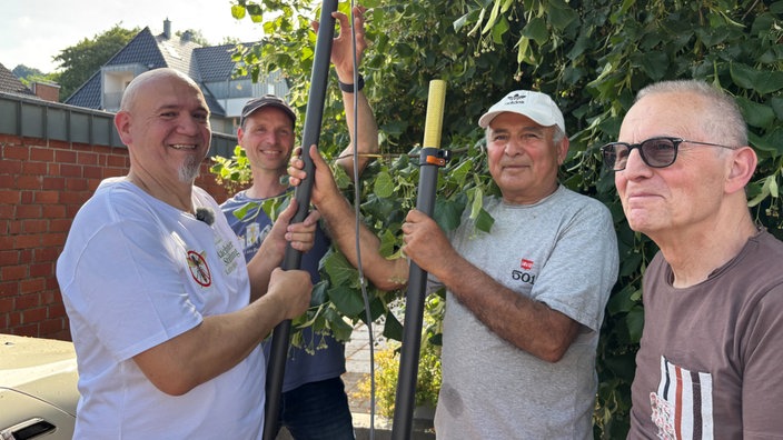 Männer vor einem Baum mit einer Teleskopstange aus Carbon