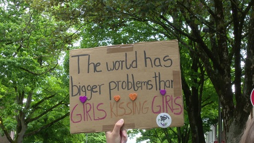 Auf einem Pappschild steht "The world has bigger problems than girls kissing girls"