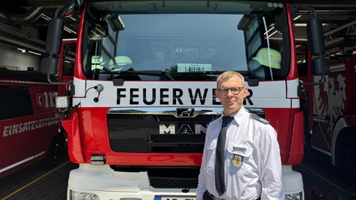 Einsatzleiter Markus Hugot vor einem Feuerwehrauto.
