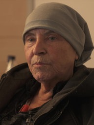 Hospizbewohnerin Ursula Dickmeis sitzt mit einer Mütze bekleidet in einem Raum im aachener Hospiz Haus Hörn