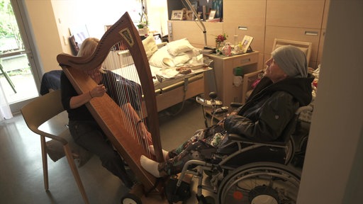 Eine Patientin drückt ihre Füße gegen die Harfe, während sie gespielt wird.