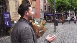 Ein Mann mit einem Blumenstrauß in der Hand in der Innenstadt von Aachen