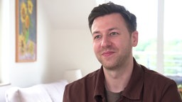 Ein Mann mit dunklen Haaren lächelt