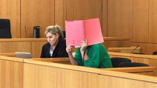Der Angeklagte in grüner Kleidung neben seiner Anwältin vor der Urteilsverkündung.