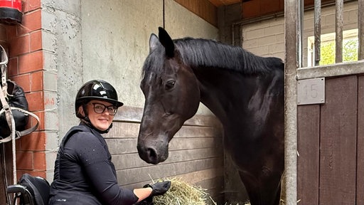 Annika Brunkhorst mit ihrem Pferd in einem Stall 